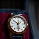 A hand presenting a vintage watch in a display case, symbolizing investment